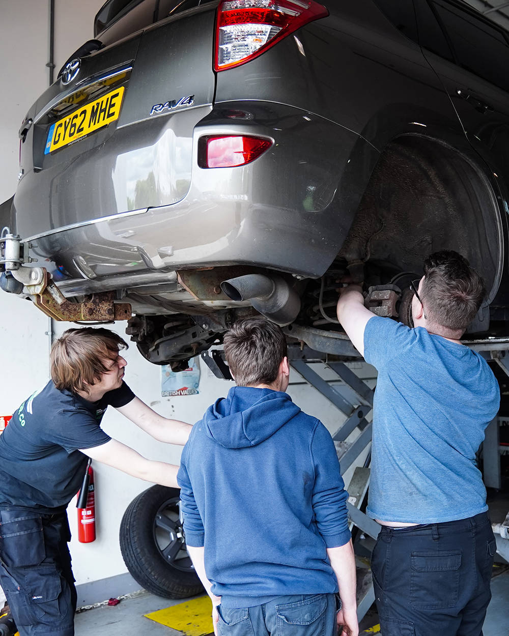 Automotive students working with car on ramp