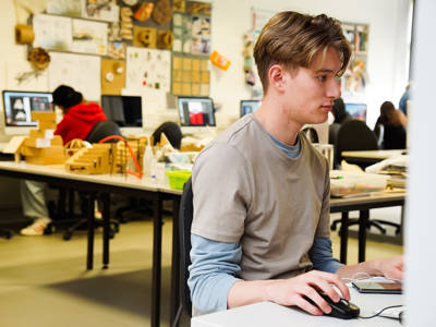 A male student using a computer in an art and design classroom
