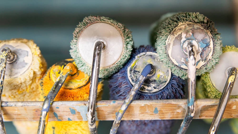 Colourful painting and decorating rollers stacked up in drying rack