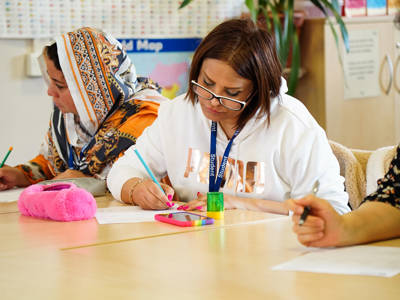 Adult learners writing on worksheets during a classroom session.