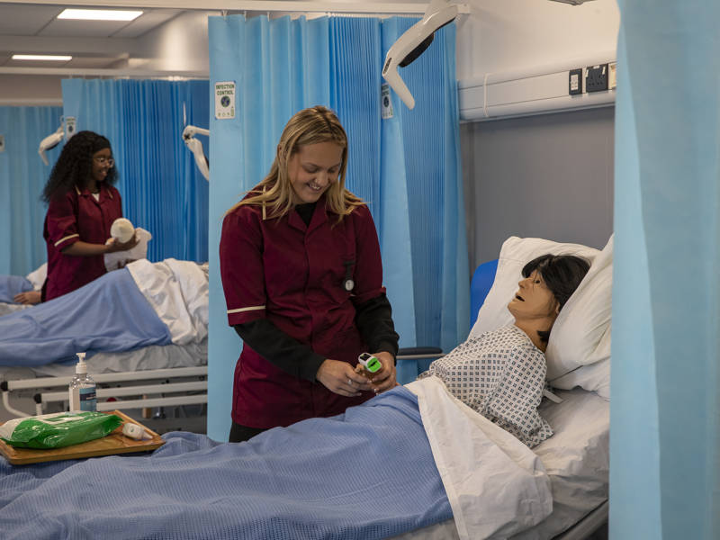 Two Health and Nursing students tend to patients in the training ward at City of Portsmouth College