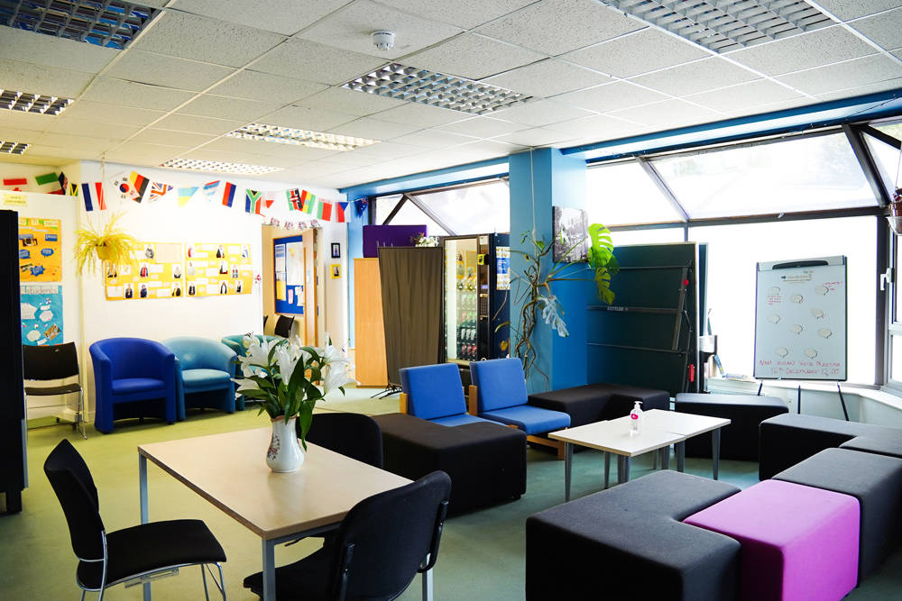 Adult learning hub social and study space with seating, tables and noticeboards.