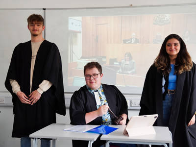 Three students wearing law clothing practicing for the courtroom