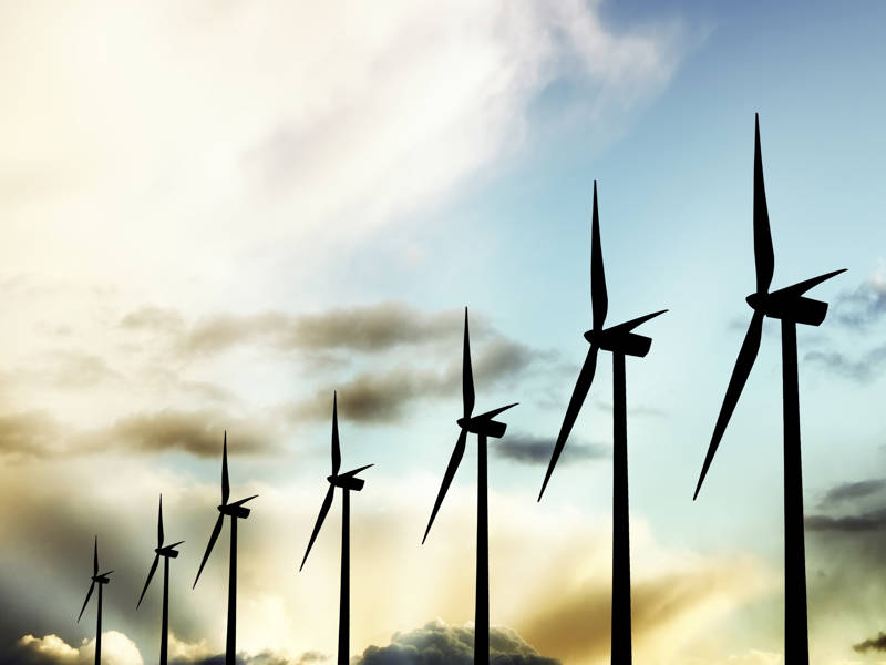 Wind farm silhouetted against a cloudy sky.