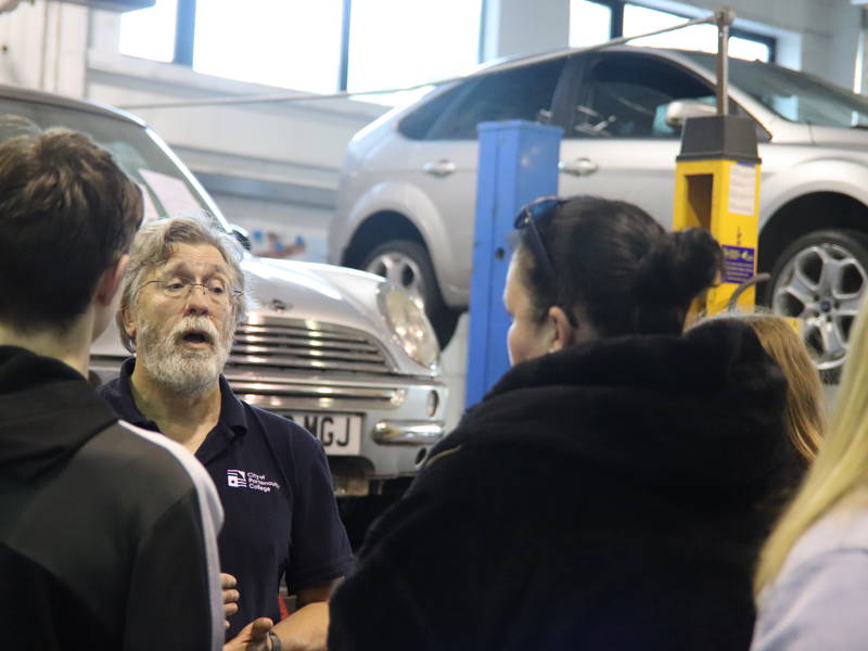 A lecturer is seen talking to a family in the automotive department.