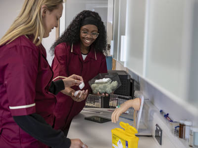 Two healthcare students learning how to put in a cannula. 