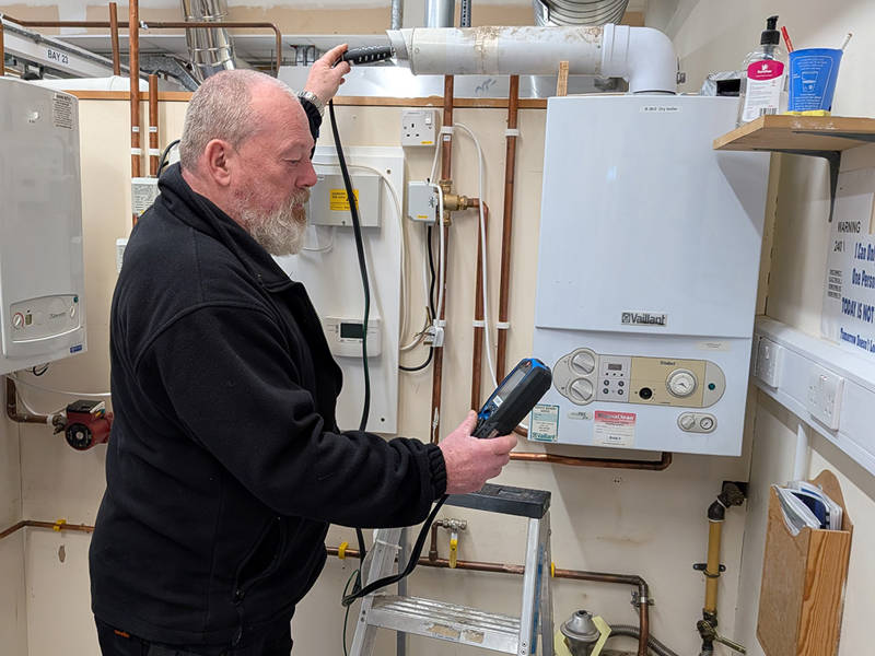 Gas engineer using a flue gas analyser to test a boiler during initial ACS CCN1 gas safety training and assessment.