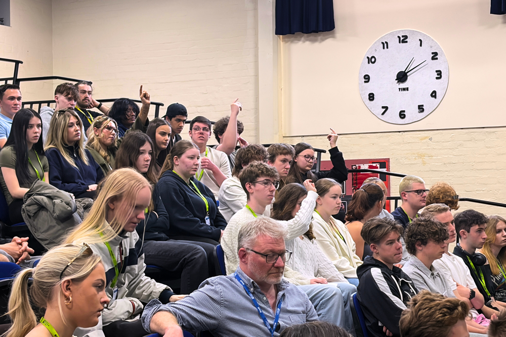 Students raise their hands in the audience for the City of Portsmouth College hustings 2026