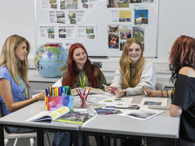 Female students sitting around a table studying travel and tourism 