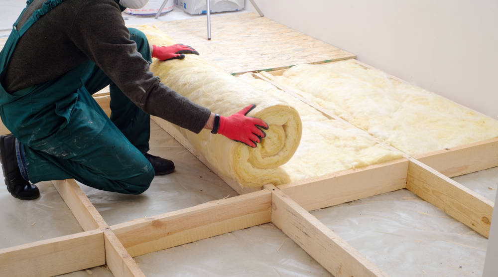 Worker insulating the floor with mineral wool.
