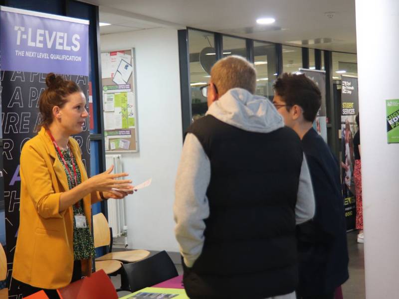 Prospective student and parent talking to staff member at T Level table during Open Event.