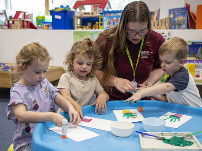 A T Level Childcare student painting with children in the nursery 