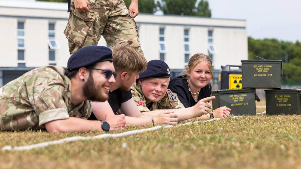 Group of UPS students in uniform lying on the grass during an outdoor training exercise.