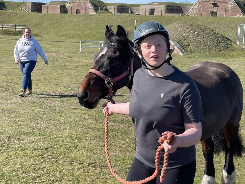 Smiling girl Animal Care student leading pony at Fort Widley.