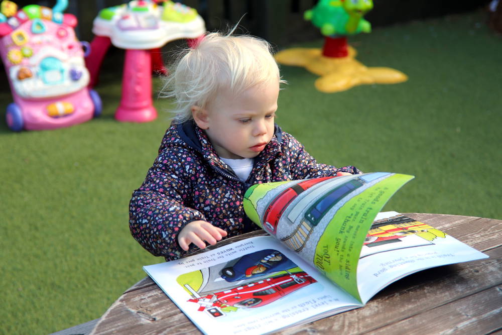 Small blonde child looking at a book.
