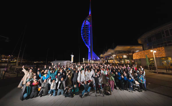 A group of people cheering in front of Portsmouth's Spinnaker Tower