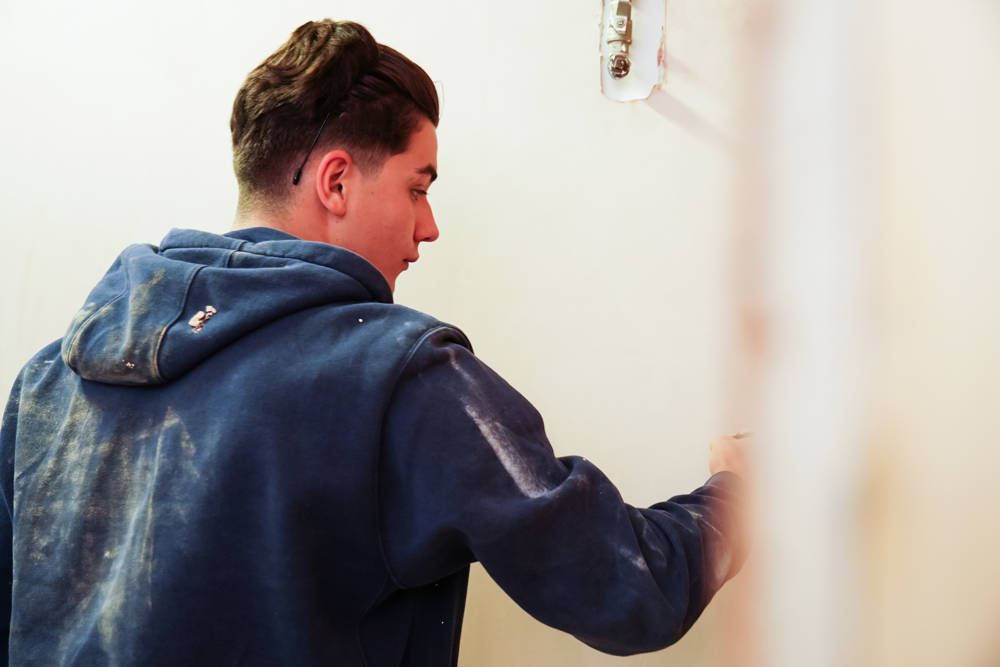 A young student plastering a wall