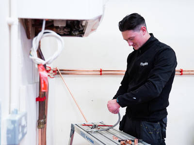 A plumbing student installing a flexi hose 