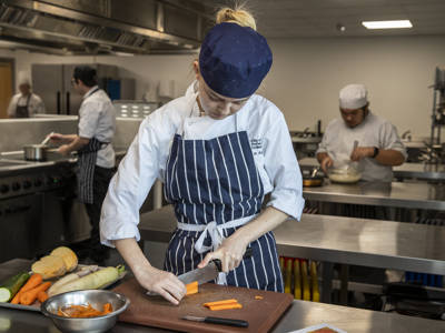 A student chopping vegetables in a commercial training kitchen 