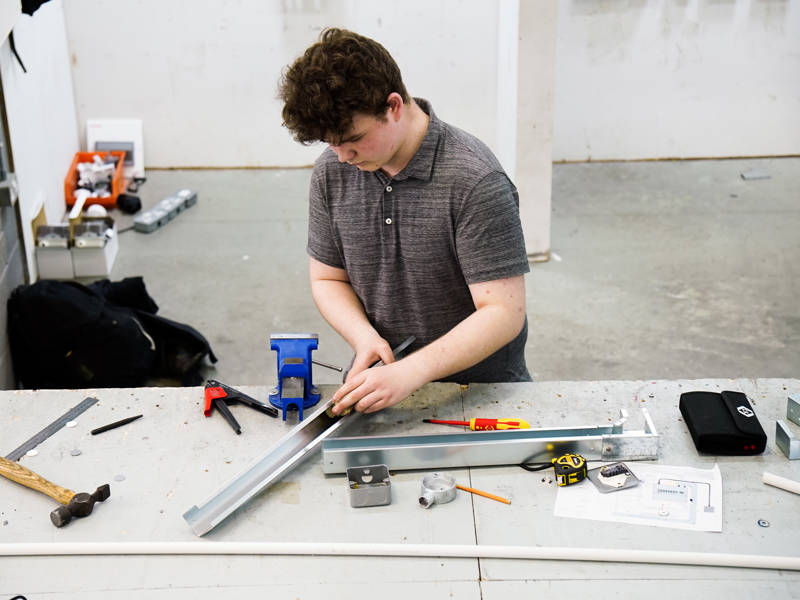 Young male student at a workbench as part of his Level 3 Electrical Installation/Maintenance (Electrician) Apprenticeship Standard.