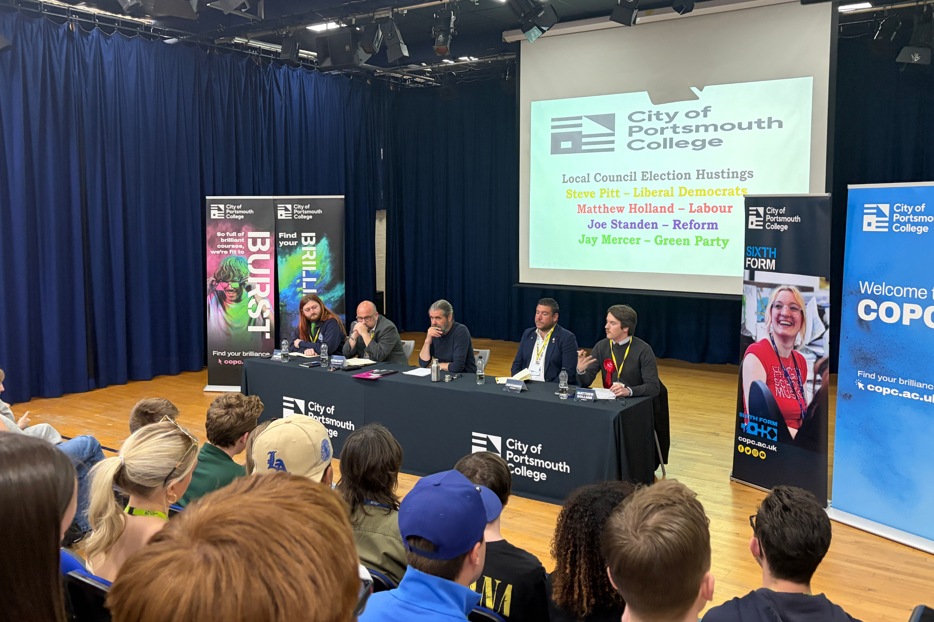 The City of Portsmouth College hustings 2026, showing four candidates and politics lecturer Steve Fitzgerald, centre, at a table in front of an audience of students